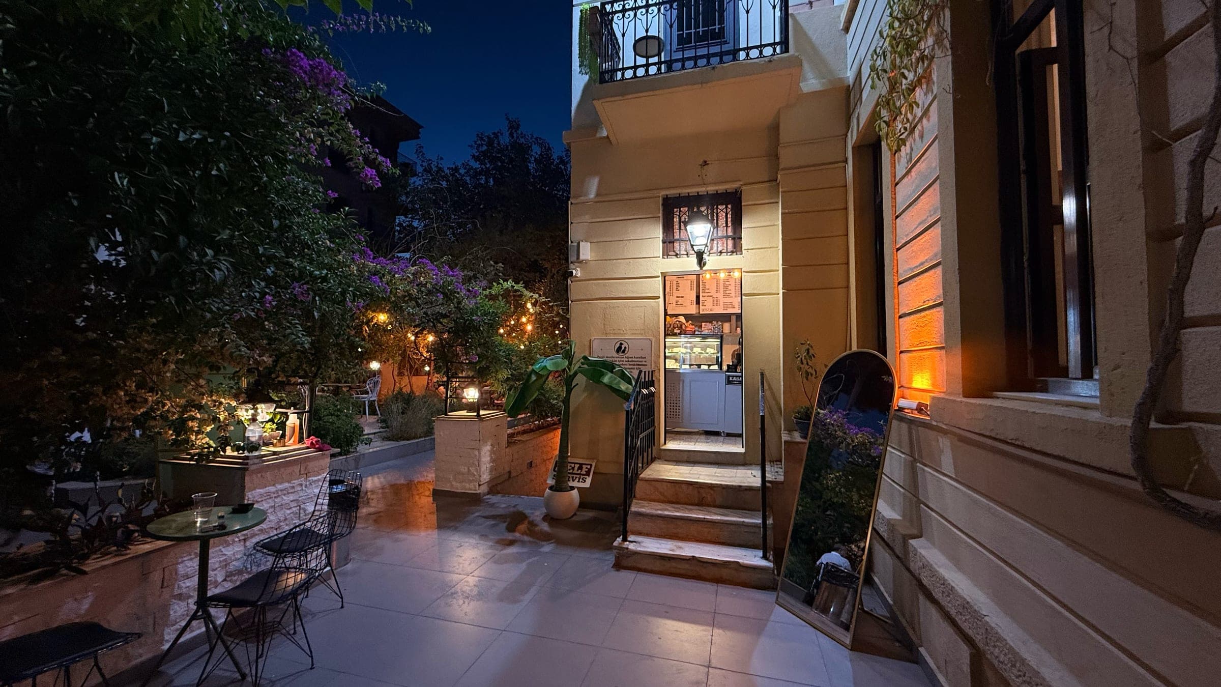Çiçekli ağaçlarla çevrili avlu ve kafe girişi